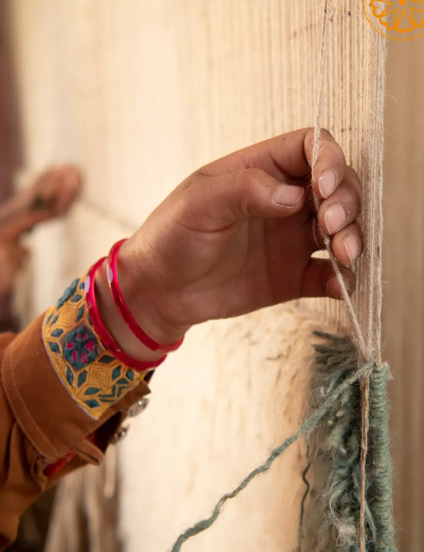 Woman wearing traditional green and red patterned clothing and red bangles.